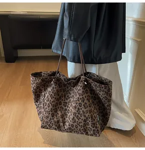 Detail of leopard print tote bag featuring a white logo tag and slim brown handles