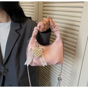 Detail of pink pleated hobo bag with silver chain strap and pearl heart charm