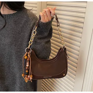 Detail of dark brown crescent bag with gold chain strap and vintage wooden bead tassel