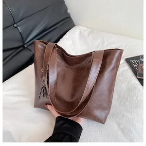 Détail du sac cabas marron foncé montrant la texture plissée brillante et l'étiquette