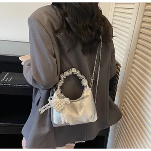 Silver wrinkled hobo bag with pearl heart charm and lace bow detail on a stylish model