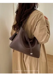 Detail of dark brown lychee textured leather hobo bag with long side tassels on model