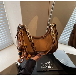 Detail of retro brown patchwork shoulder bag with chunky gold chain and beaded tassel
