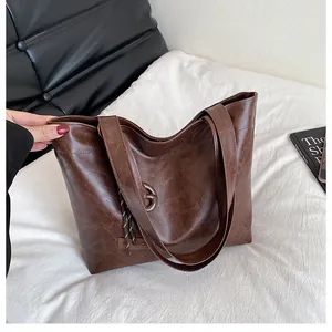 Détail du sac cabas marron foncé en cuir vintage avec étiquette mode et pompon