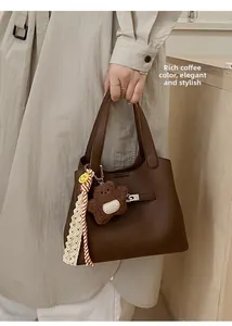 Detail of coffee bucket bag in lychee pattern leather with a cute bear charm