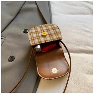 Detail of plaid mini crossbody bag showing magnetic closure and interior lipstick space