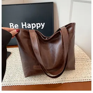 Détail d'un sac cabas en cuir PU marron avec une texture grainée et une étiquette de mode