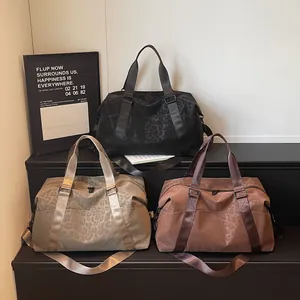 Three leopard print travel duffel bags in black, khaki, and purple on a display
