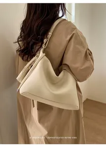 Minimalist beige hobo bag with pebble leather texture worn by a model in interior