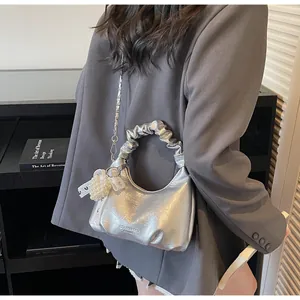 Detail of silver pleated handbag with chain strap and beaded pendant decoration