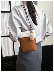 Détail du sac bandoulière en daim marron avec bordure en fausse fourrure sur un modèle