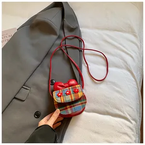 Close-up of a mini plaid crossbody bag with red bow and small floral embroidery details