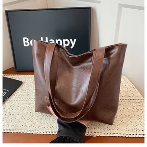 Gros plan d'un sac cabas marron vintage montrant la texture du cuir PU et le logo