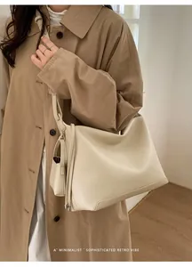 Chic cream tote bag with grain leather texture and a matching mini pouch on a model