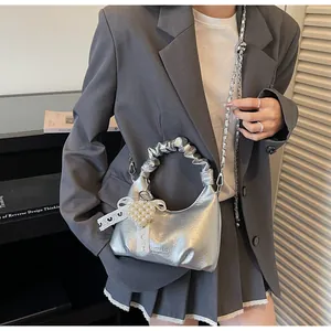 Close-up of silver pleated handbag with pearl heart charm and lace bow details