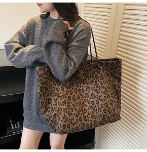 Close-up of leopard print canvas tote bag with slim brown shoulder straps on a model