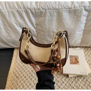 Detail of hobo bag with gold chain and ethnic style wooden bead tassel ornament