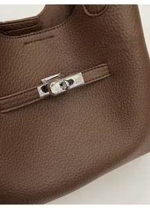 Detail of silver twist lock and lychee grain leather on dark brown bucket bag