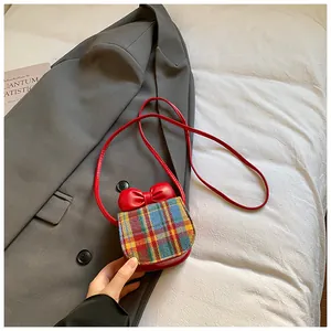 Detail of red mini crossbody bag featuring a colorful plaid flap and a 3D bow accent