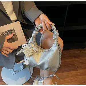 Macro detail of metallic silver hobo bag with pleated handle and pearl bow charm