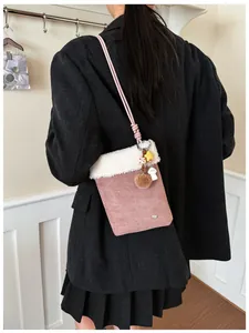 Détail du sac bandoulière rose en daim avec bordure en laine de mouton et breloques