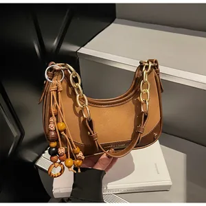 Detail of vintage brown crescent bag with gold chain and exotic beaded tassel