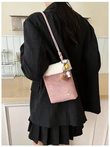 Détail du sac bandoulière en daim rose et polaire blanche avec breloques étoile et fourrure