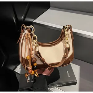 Detail view of contrast stitching handbag with gold chain strap and beaded charm