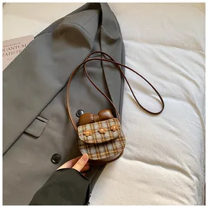 Detail of mini checkered crossbody bag with 3D floral accents and leather bow detail