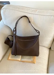 Close-up of deep brown lychee leather texture on a minimalist shoulder bag with mini pouch