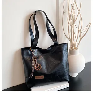 Détail du cabas noir en similicuir avec étiquette mode et charm de sac en forme de bretzel