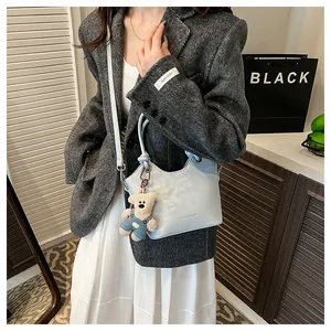 Detailed shot of a light blue bucket bag with a cute teddy bear charm and brand engraving