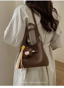 Detail of dark brown pebble leather bucket bag with retro metal twist lock and cute charms