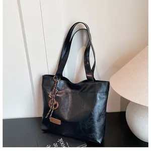 Gros plan du sac cabas noir avec texture grainée et étiquette fashion en cuir