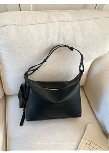 Macro detail of black litchi grain texture on minimalist leather shoulder bag