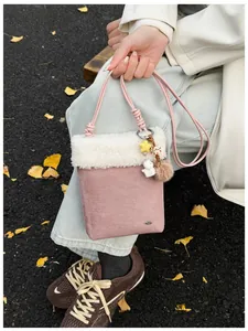 Détail du sac à bandoulière rose en suédine avec bordure en peluche et breloques en automne