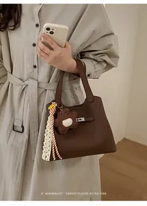 Close-up of retro brown pebbled leather bucket bag with metal lock and teddy bear charm