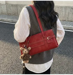 Detail of vintage burgundy shoulder bag with contrast stitching and teddy bear charm