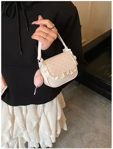 Gros plan du sac crème avec pois roses, bordure en dentelle et pendentif pompon rose
