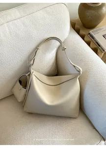 Detail of cream white pebbled leather tote bag with small matching pouch on a sofa