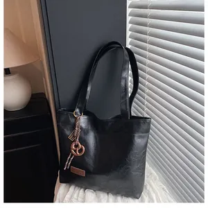 Détail d'un sac cabas noir avec pendentif biscuit et étiquette mode sur tissu doux
