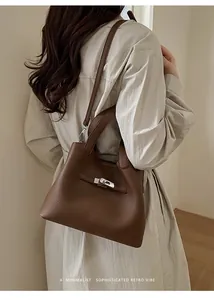 Rear view of model wearing a vintage brown lychee grain leather bucket bag with silver lock