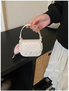 Détail du mini sac crème à pois roses avec bords en dentelle et pompon rose