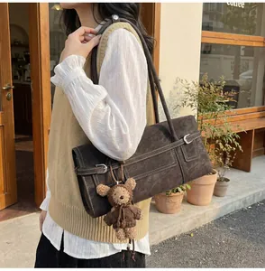 Detail of dark brown vintage faux suede shoulder bag with buckle and plush bear charm