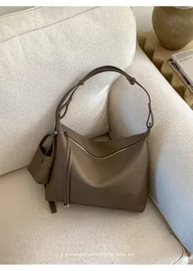 Detail of minimalist dark coffee leather tote with adjustable knot strap and mini pouch