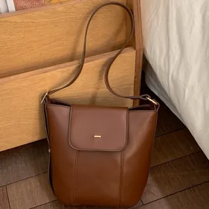 Brown oil wax leather bucket bag for women with gold clasp and adjustable strap