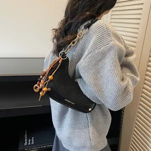 Fashionable black matte saddle bag with chunky gold chain and colorful wooden bead tassel