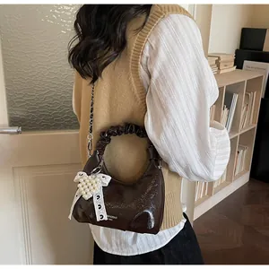 Detail of dark brown glossy mini handbag with pearl heart charm and lace bow decor
