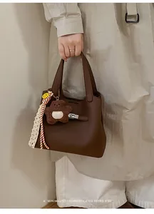 Close-up of vintage brown leather bucket bag with metal lock and cute bear charm