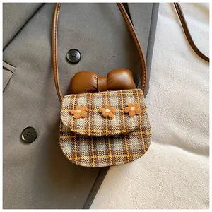 Detail of mini plaid crossbody bag with leather bow and three floral decorations